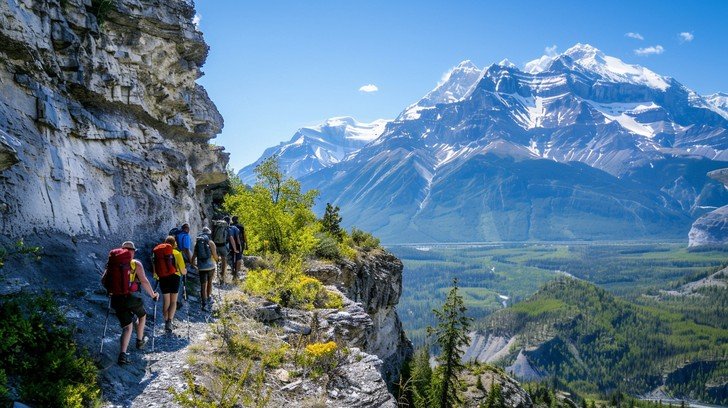 Hiker trekking along a rugged mountain trail with dramatic peaks in the background, representing adventure travel destinations